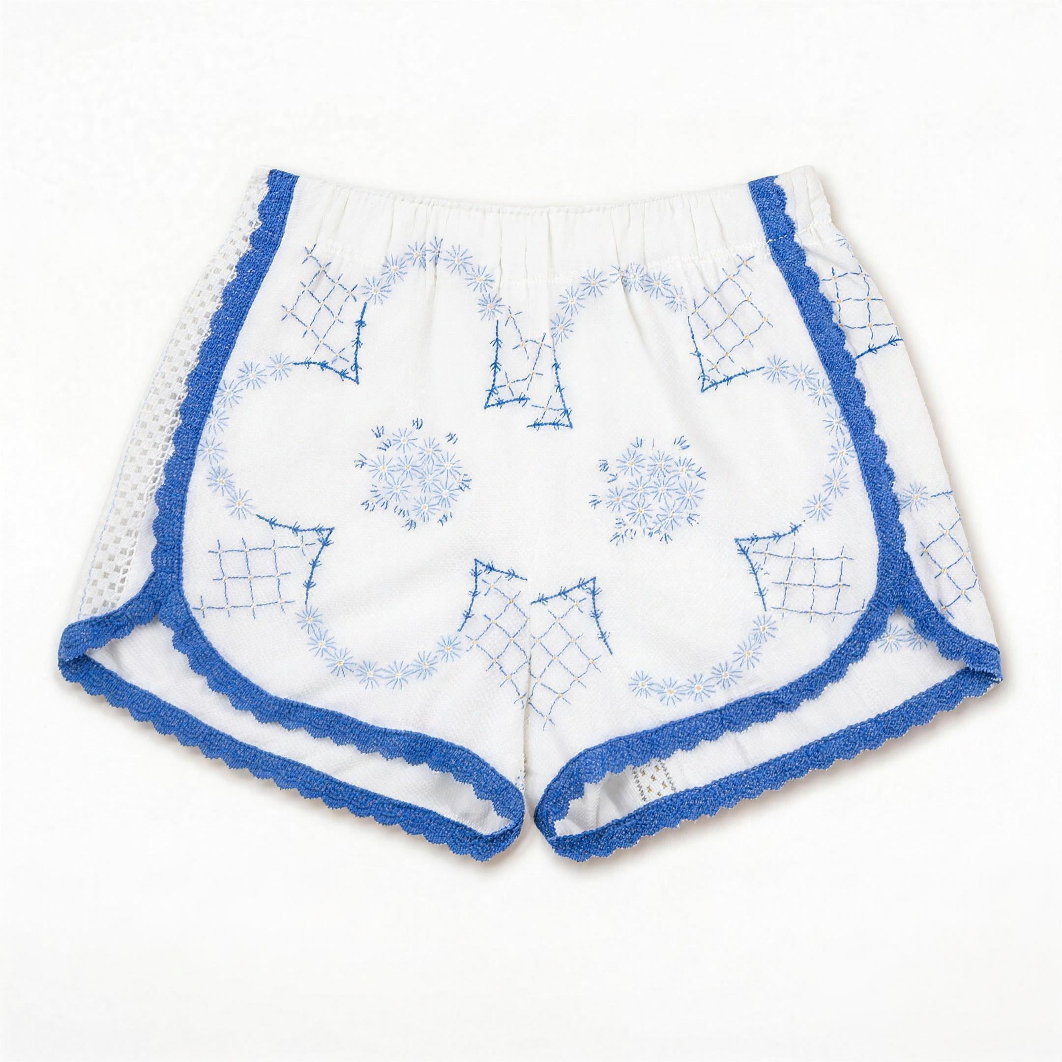 Shorts Loggia DELAMIA — ricami geometrici blu e merletto a giorno su bianco, vista frontale