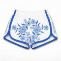Shorts Ortensia DELAMIA — fioritura azzurra a punto croce su bianco, vista frontale